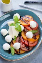 Close-up of a turquoise plate with caprese salad, vertical shot, selective focus
