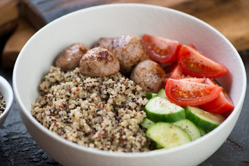 Close-up of a food bowl with quinoa, fried meatballs and fresh vegetables, selective focus