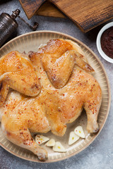 Close-up of fried chicken tabaka served on a beige plate, vertical shot, flatlay