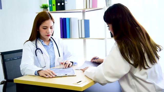 Two women doctors consultation with professional specialist diagnostics at hospital medicare treatment clinic. Doctor writing prescription for medical health care oncologist therapy using laptop. 