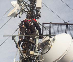Electrician man climbing on pole to repair antenna