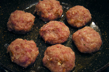 Raw meat cutlets rissole meatballs of minced pork in a pan.