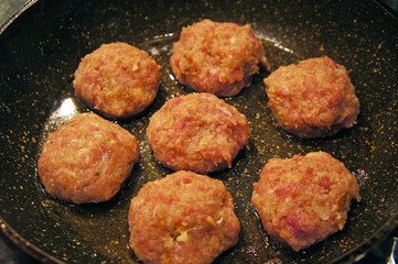 Raw meat cutlets rissole meatballs of minced pork in a pan.