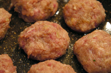 Raw meat cutlets rissole meatballs of minced pork in a pan.