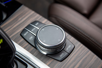 multimedia system control wheel on a wooden panel in a modern premium luxury exencive new car. close-up, soft focus.