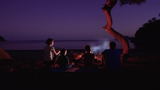 Tourist family near the campfire at night. Freedom and travel concept. 4K