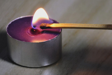 Close up of lighting a purple candle with matchstick