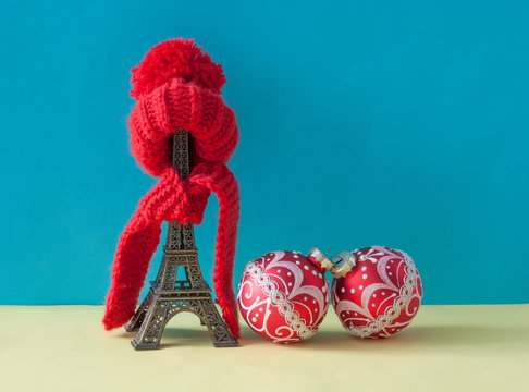 Christmas decoration with eiffel tower statue in red scraf and hat  on colorful paper background. Holiday background with copy space