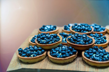 Blueberry tarts arranged in rows on a wooden board. 