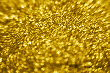Golden color glitter background. Blurred monochrome background with bokeh. Blurred glitters shimmering dust macro close up.