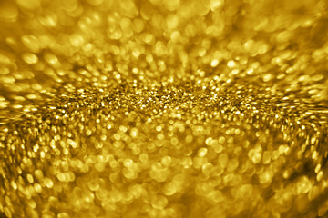 Golden color glitter background. Blurred monochrome background with bokeh. Blurred glitters shimmering dust macro close up.