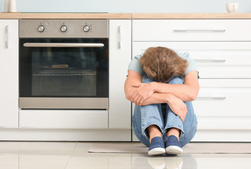 Depressed man in kitchen at home