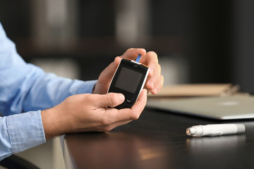 Diabetic man checking blood sugar level in office, closeup