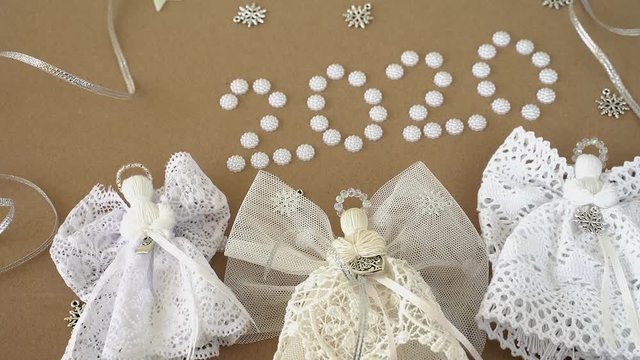 Christmas 2020 decorations on paper background. Angels, text "2020", lace and pearls	