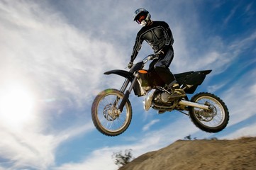 Motocross Racer In Midair Against Cloudy Sky