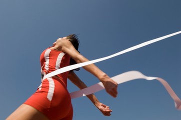 Female Athlete Crossing Finish Line Against Blue Sky