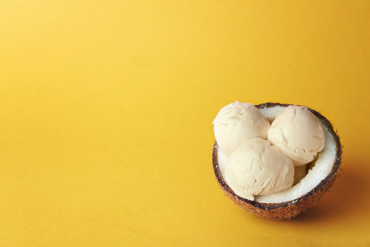 Coconut with tasty ice-cream on color background