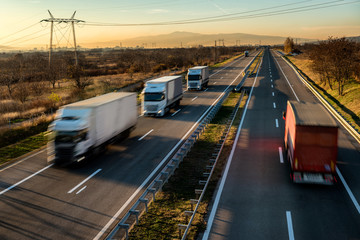 Delivery trucks in high speed driving on a highway through rural landscape. Fast blurred motion...