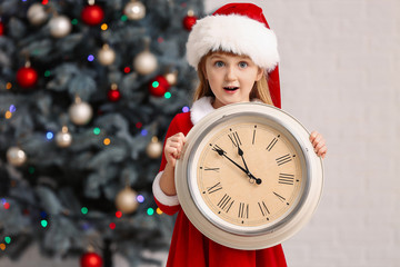 Little girl in Santa costume and with clock at home. Christmas countdown concept