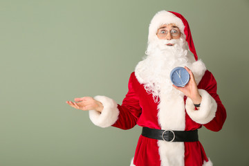 Surprised Santa with alarm clock on color background. Christmas countdown concept