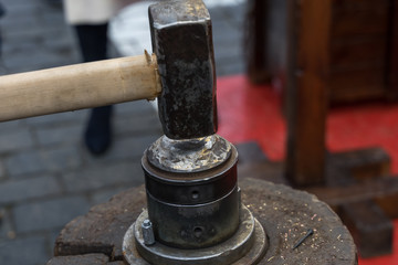 .minting coins at a street festival. the boy hits the anvil with a hammer