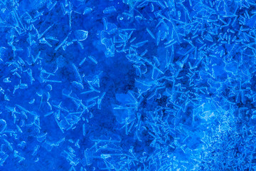 blue texture of an ice surface with pure azure water ,cold snow cryslallized wall background ,winter frozen lake side close up , abstract macro wallpaper