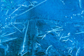 blue texture of an ice surface with pure azure water ,cold snow cryslallized wall background ,winter frozen lake side close up , abstract macro wallpaper