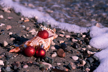 Christmas balls, seashell and pebbles at the beach