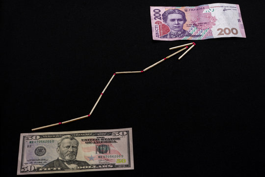Ukrainian hryvnia and US dollar with arrow on black background.