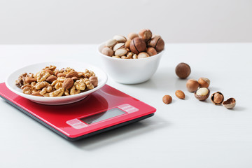 mix of different nuts on  kitchen scale on a white table