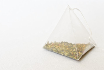 One tea bag is a pyramid with green tea and aromatic fruits. White background. Free space for an...