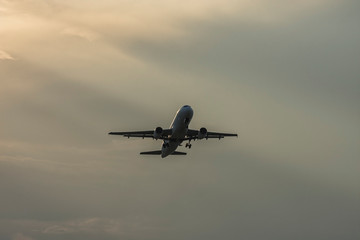 Landing airplane at colorful sunset. Silhouette, selective focus. Landscape, background.