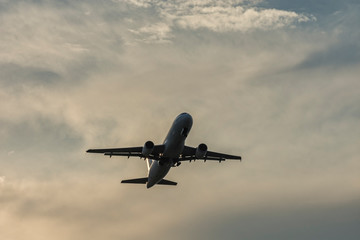 Landing airplane at colorful sunset. Silhouette, selective focus. Landscape, background.
