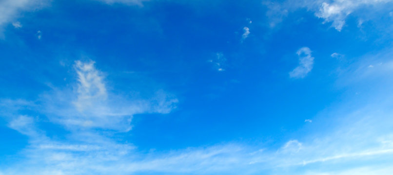 White clouds in the blue sky . Wide photo .