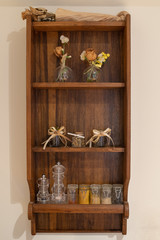 Wooden shelf with some spices, glasses and flowers as decorations
