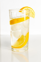 Glass of water with ice and slices of lemon on a white background.