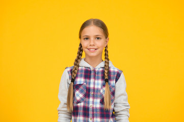 cute smile. hipster girl yellow background. happy school girl casual style. kid fashion. child cute blond hair. childhood happiness. happy childrens day. small girl checkered jacket. autumn time