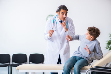 Fototapeta premium Young male doctor pediatrist and boy in wheel-chair