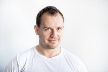 Obraz premium Closeup portrait of serious 30 years old caucasian white man on white background in white t-shirt. Confident happy smart modern man looking in camera. Lifestyle. Space for text
