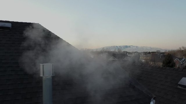 Winter morning sunrise with rooftop heater vent blowing out smoke