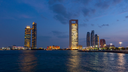 Abu Dhabi skyline at night with lights reflections on the water. Shot at blue hour. 