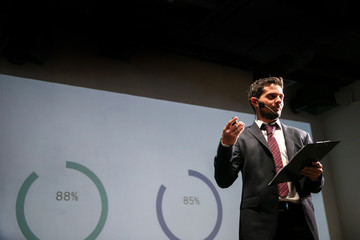 Attractive and confident successful man with headset speaking at corporate business coaching and training conference.Business and Entrepreneurship event,motivation training