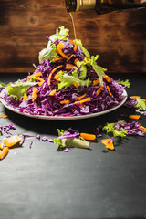 head lettuce bell pepper red cabbage salad casually scattered around a flat dish. pumpkin oil is poured from the bottle.