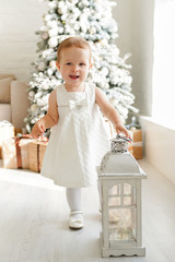 Fototapeta premium Happy small girl in white dress near christmas tree