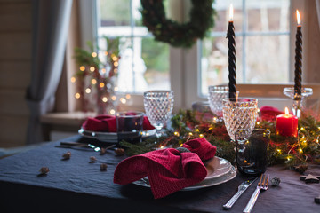 Table served for Christmas dinner, festive setting with decorations, burning candles and fir-tree branches