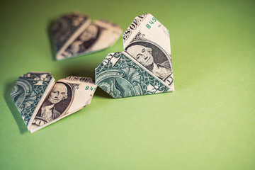 One Dollar origami hearts on a paper background. Paper craft, suitable for greed, business,...