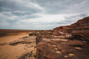 Fototapeta na wymiar Red rocks and beach on a cloudy day