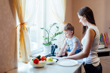 Obraz na płótnie Canvas kitchen mom son wash fruits and vegetables