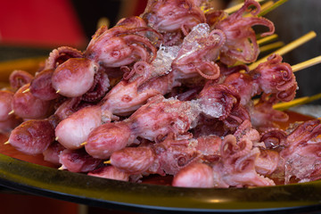 small octopuses strung on skewers, on a market stall in japan