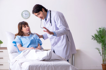 Fototapeta premium Male doctor visiting female patient in ward